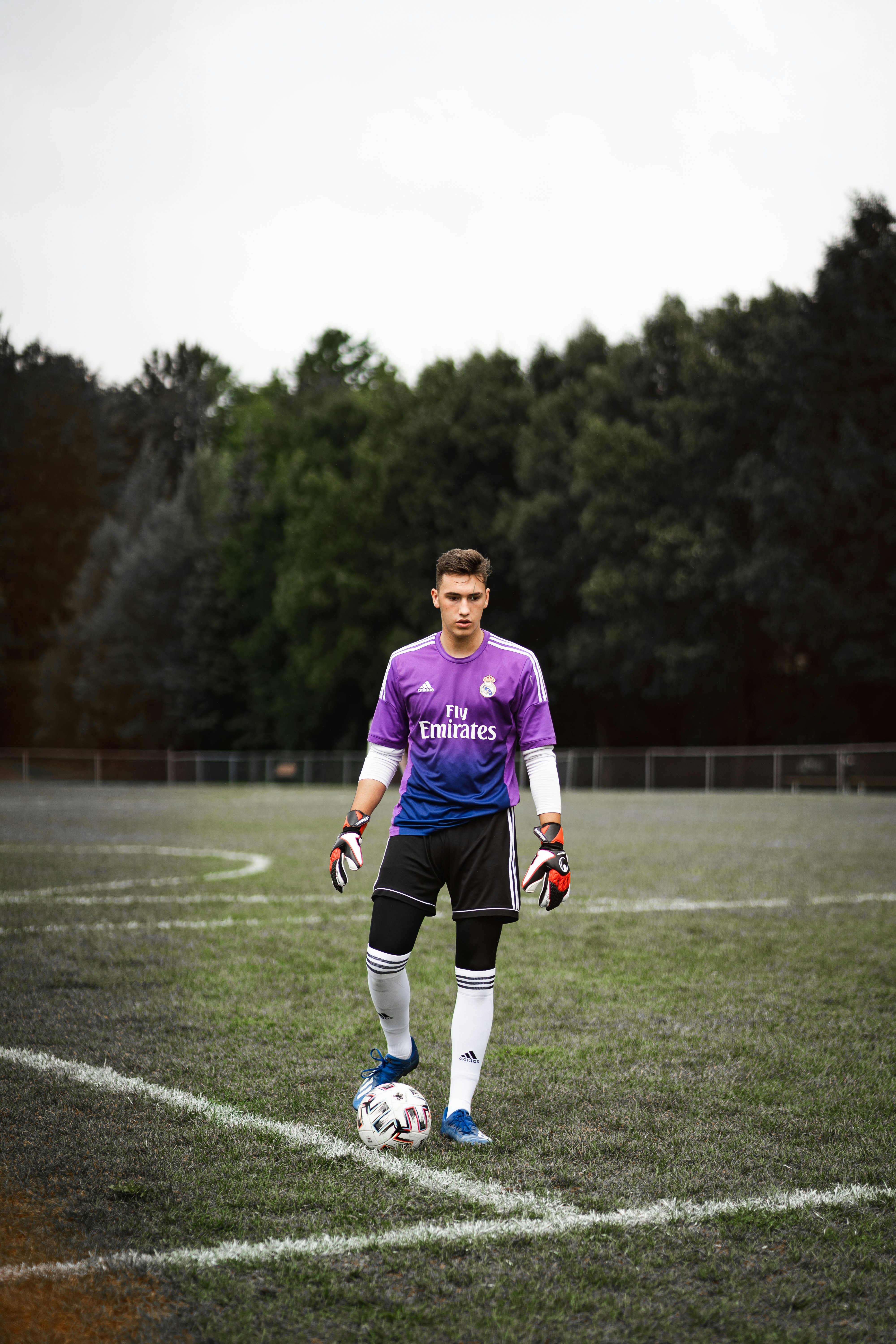 man in purple nike soccer jersey shirt and black shorts running on green grass field during